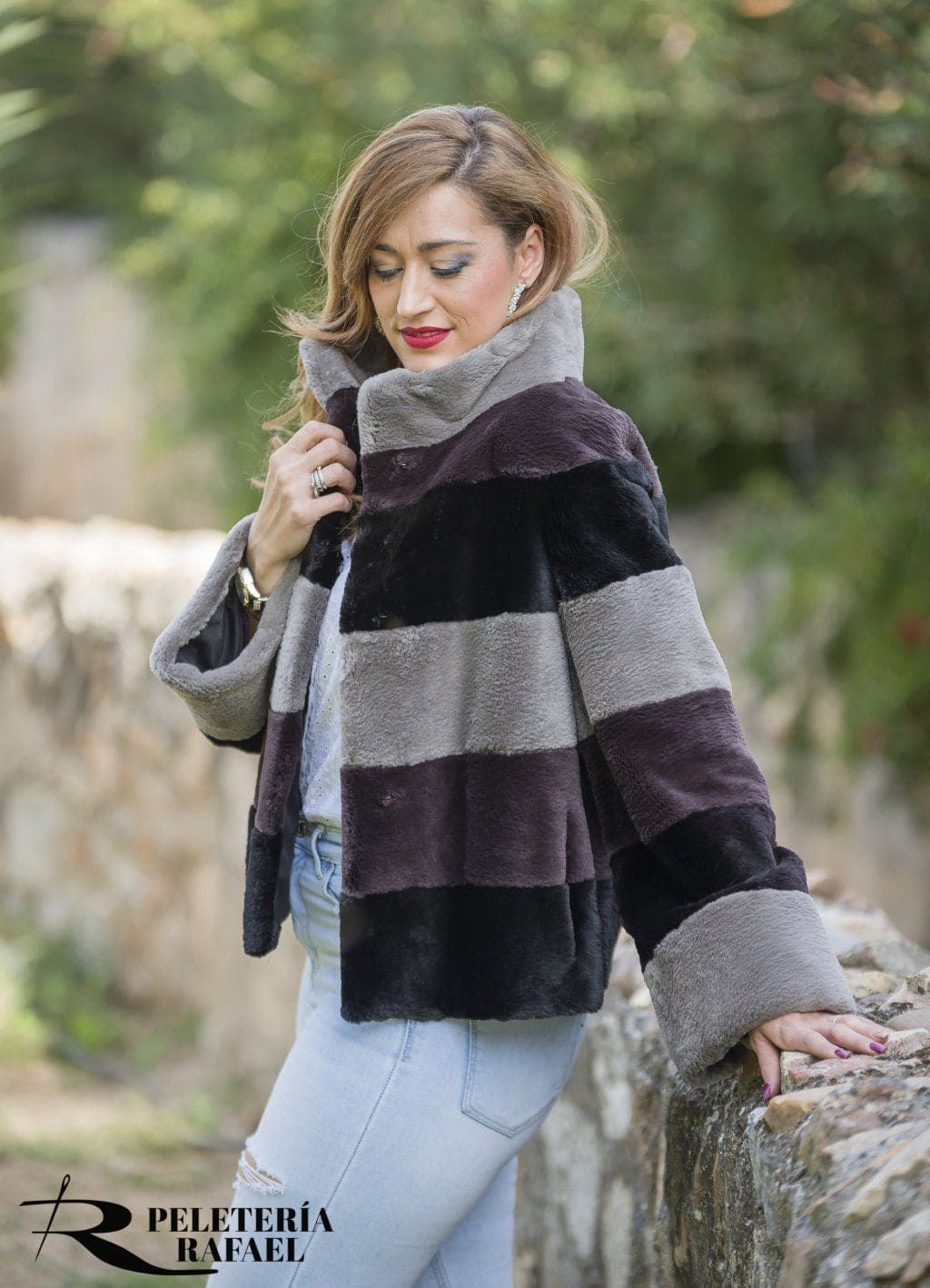 Mujer con una chaqueta de piel multicolor, posando al aire libre.