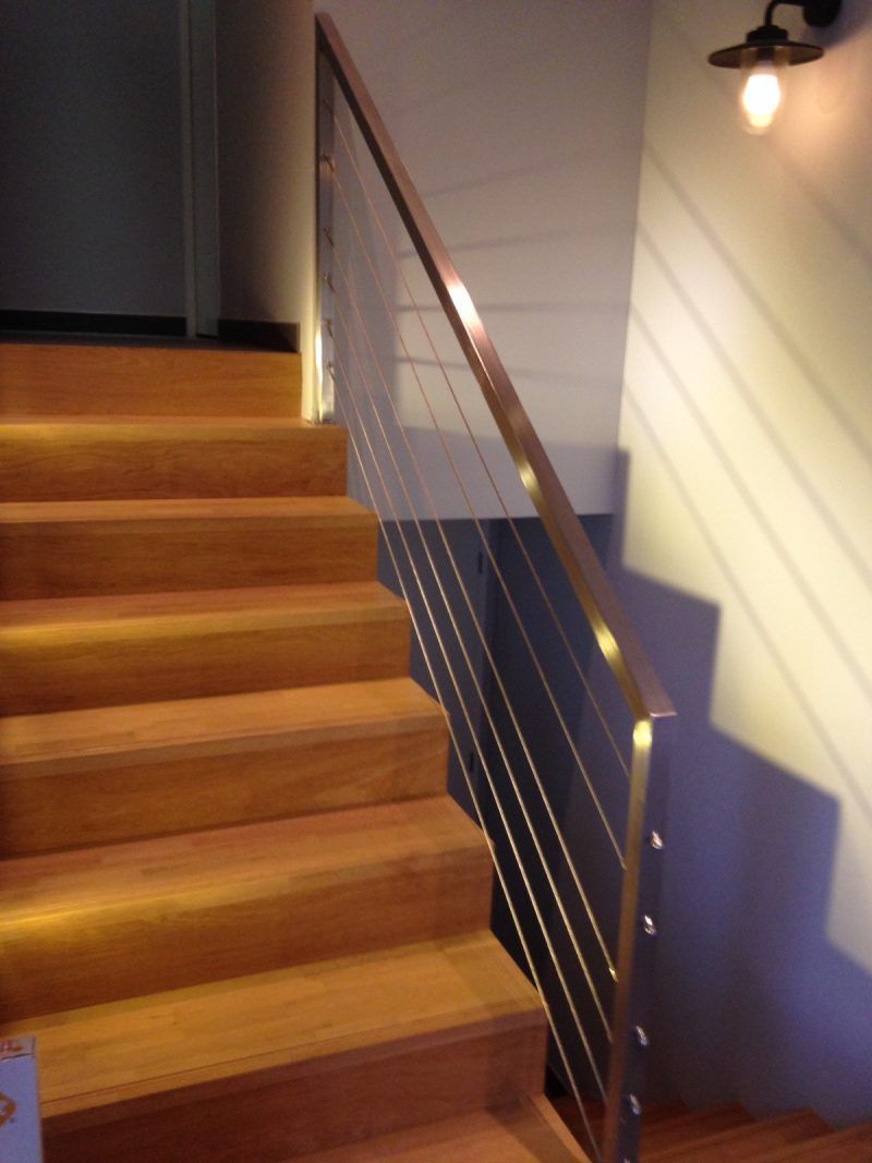 Escalier en bois avec garde-corps en câbles métalliques. Applique murale.