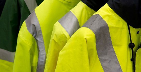 Des gilets de sécurité jaune vif avec des bandes réfléchissantes, alignés en rang.