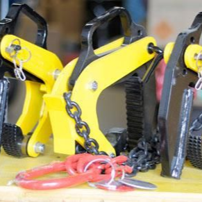Pinces de levage métalliques jaunes et noires avec chaînes, posées sur une surface.