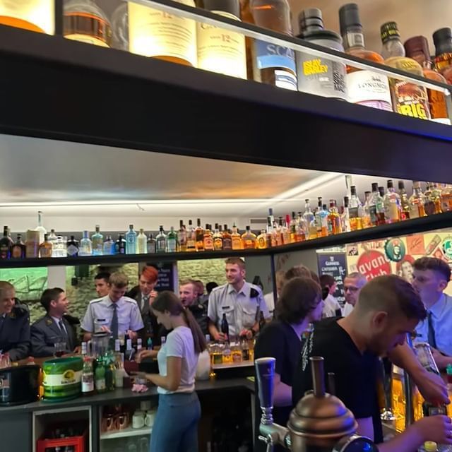 Eine Gruppe von Menschen versammelt sich in der Bar mit vielen Alkoholflaschen in den Regalen. Foto von der Havanna Brugg GmbH