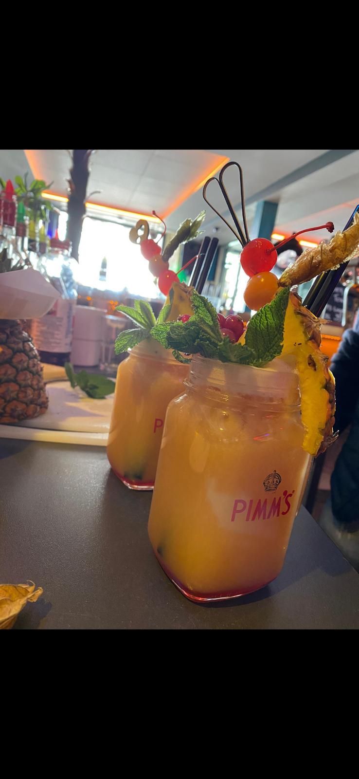 In einer Bar giesst ein Barkeeper einen Drink in ein Glas.