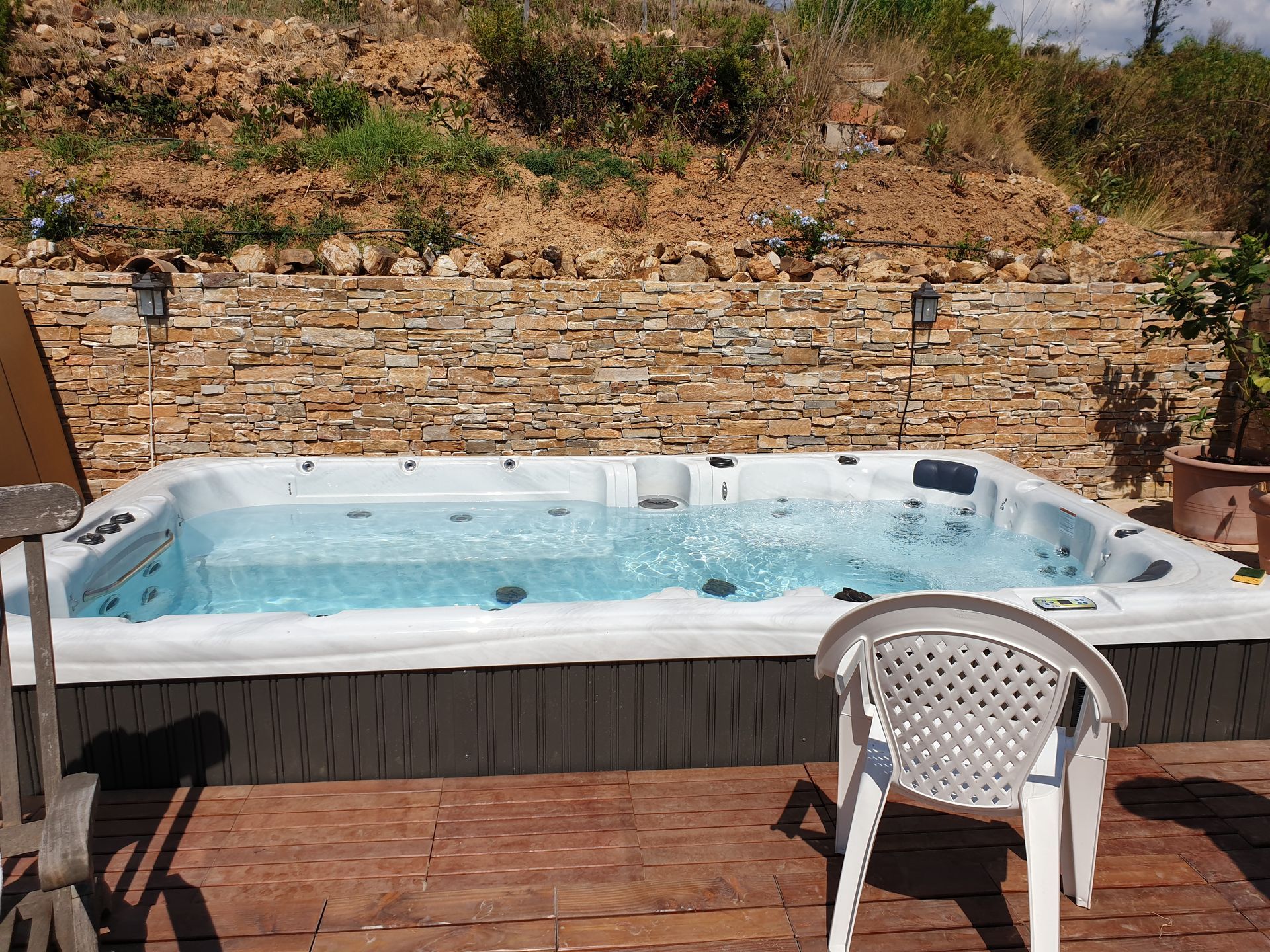 Main tenant un kit de test d'eau de piscine bleu au-dessus d'une piscine transparente. Le kit contient des liquides colorés et des bandelettes réactives.