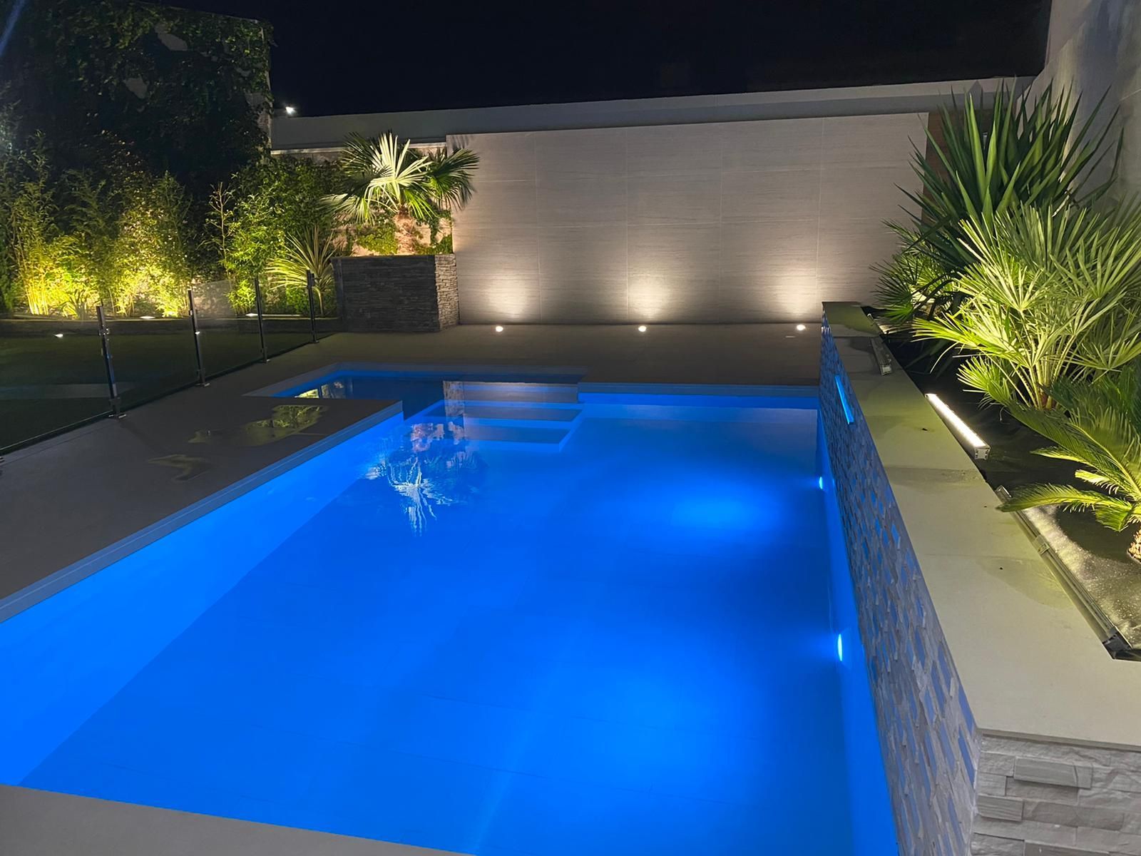 Una piscina está iluminada por la noche con luces azules.