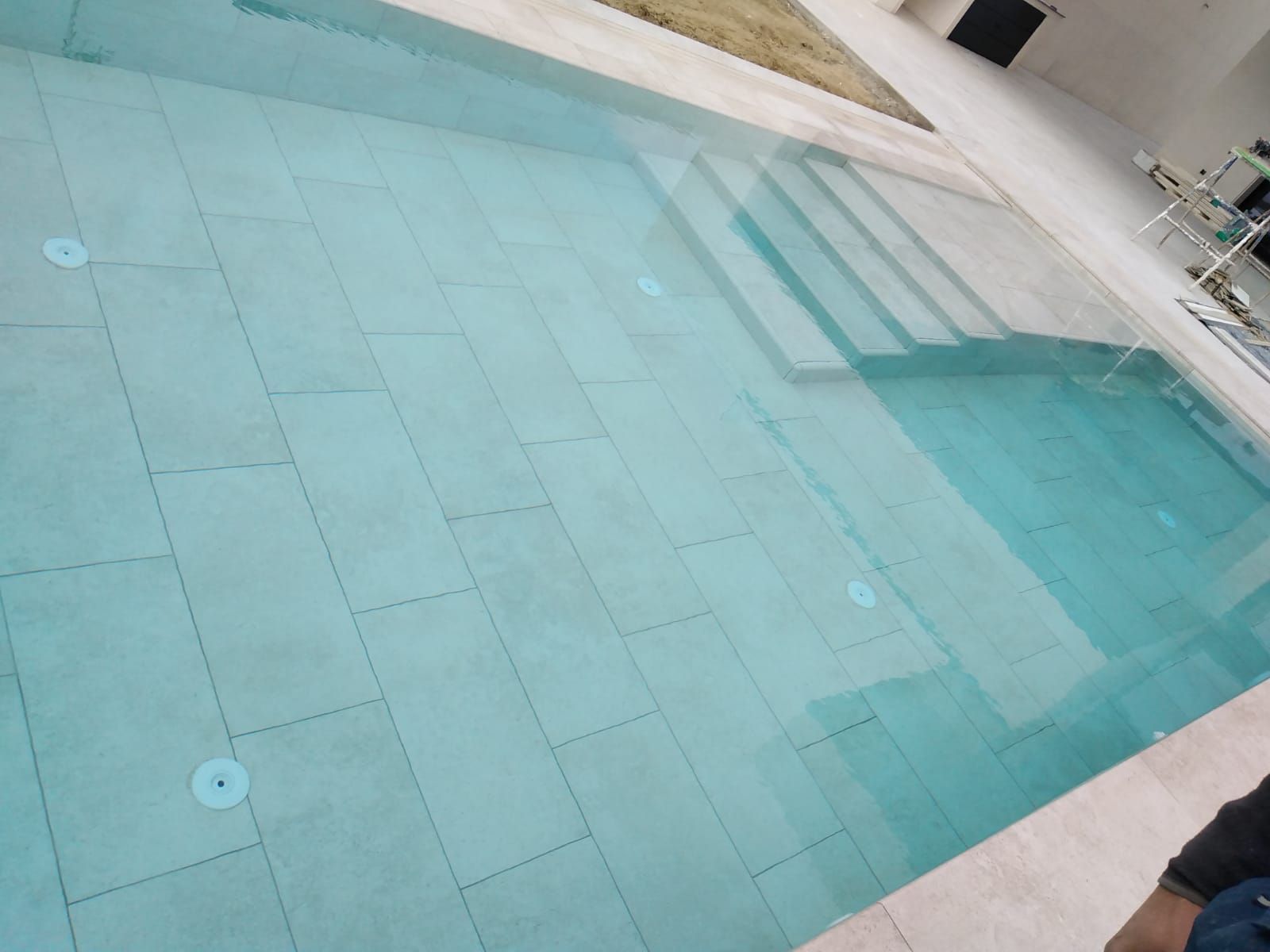 Una persona está parada al lado de una gran piscina.