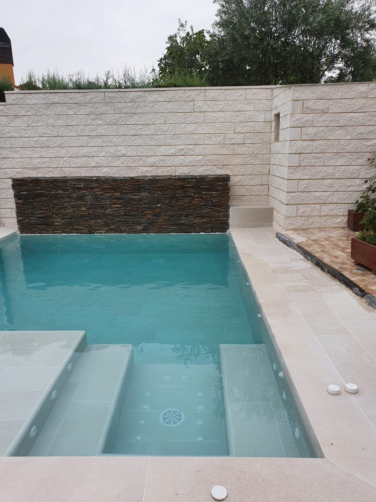 Una gran piscina con escaleras y un muro de piedra que la rodea.