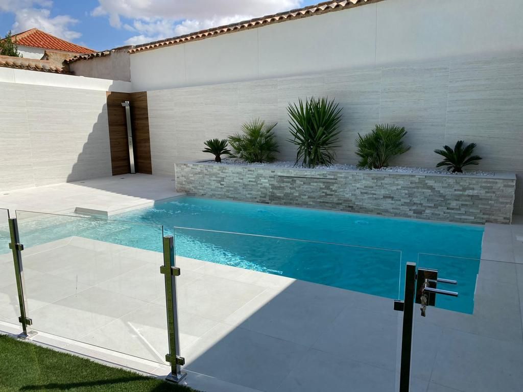 Una gran piscina con una valla de cristal a su alrededor.