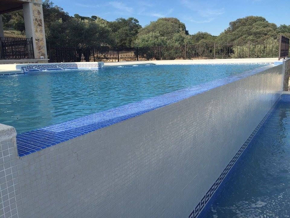 Una gran piscina con borde de azulejos azules y blancos.