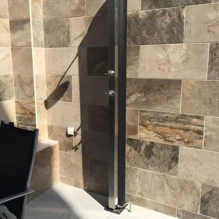 Una silla negra está colocada delante de una pared de azulejos.