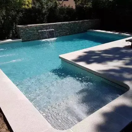 Una gran piscina con cascada en el patio trasero.