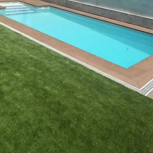 Una gran piscina está rodeada de un exuberante césped verde.