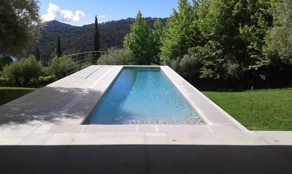 Una gran piscina rodeada de césped y árboles.