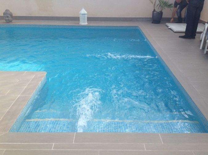 Un hombre está de pie junto a una gran piscina.