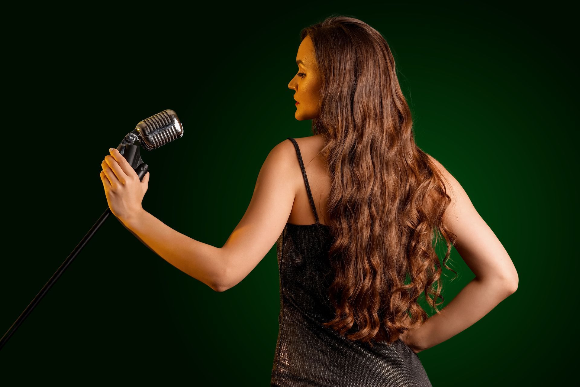 Une femme brune aux cheveux longs de dos avec un micro