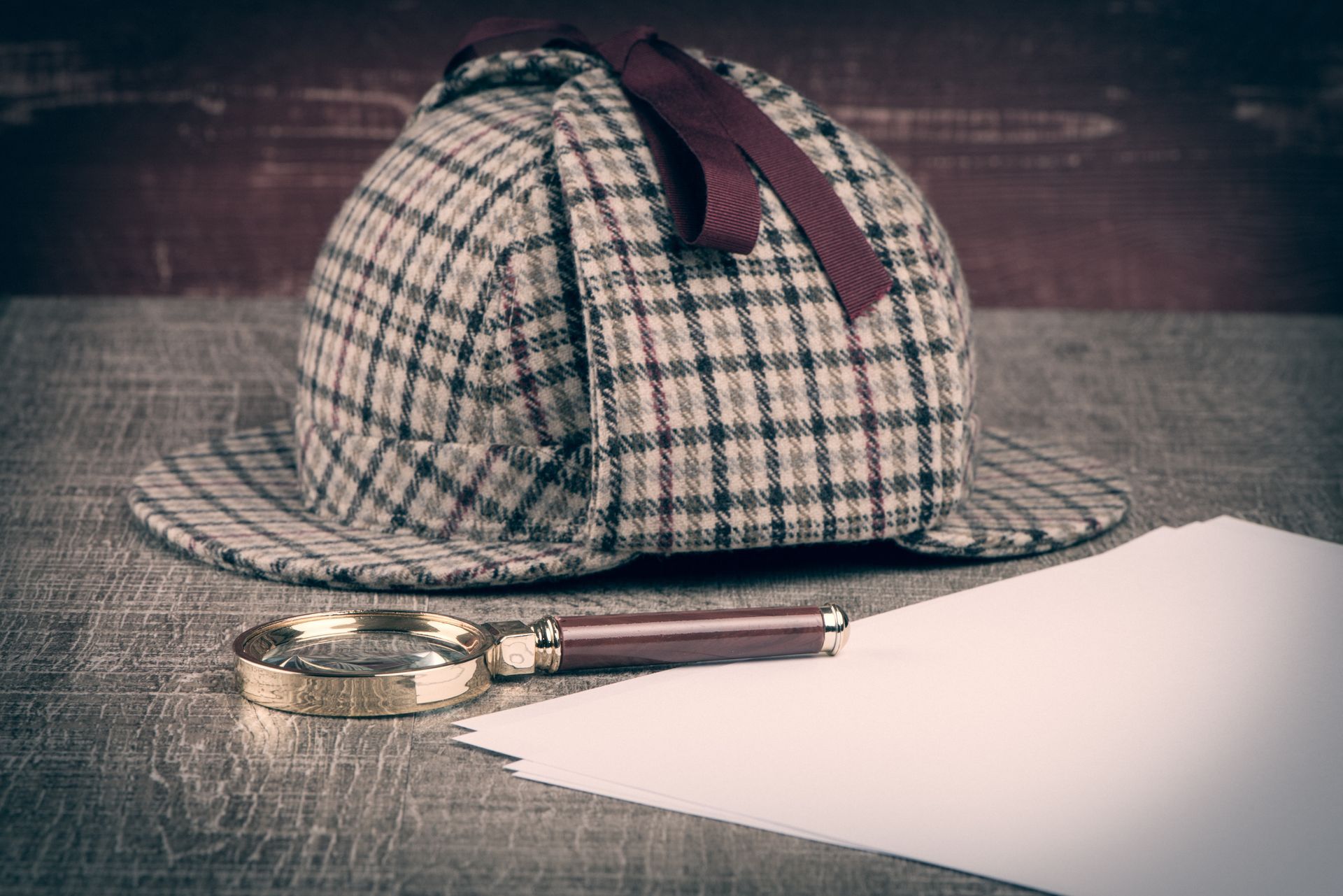Casquette de détective avec une loupe et une feuille de papier blanche