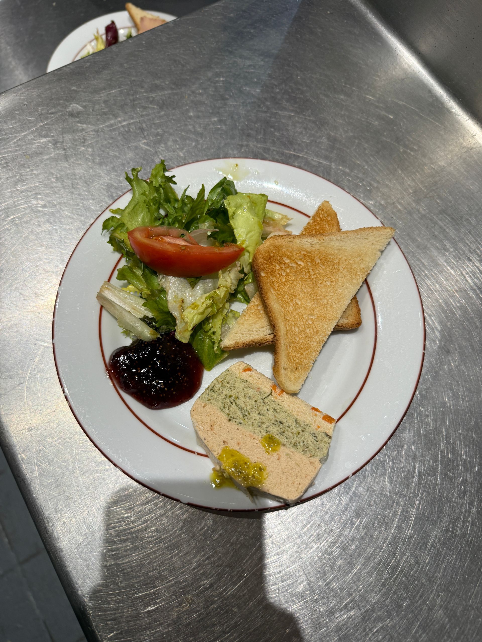 Terrine aux 3 poissons avec deux toasts, une salade et une sauce