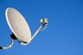 Una antena parabólica blanca contra un cielo azul.