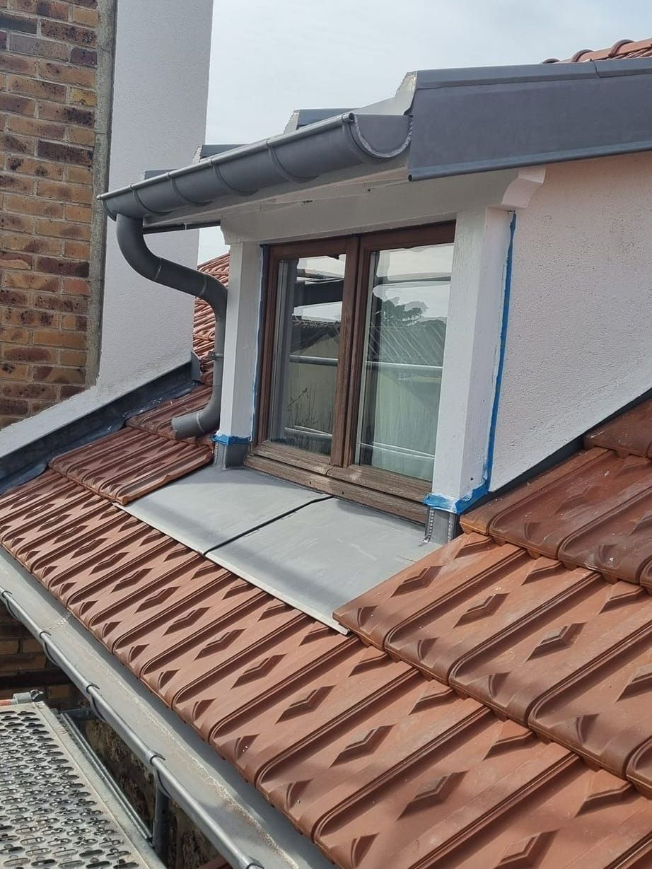 Des gouttières sur un toit et autour d'une fenêtre