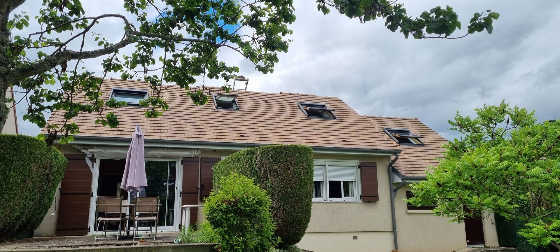 Une maison avec un toit en tuiles plates rénové et des fenêtres de toit ouvertes