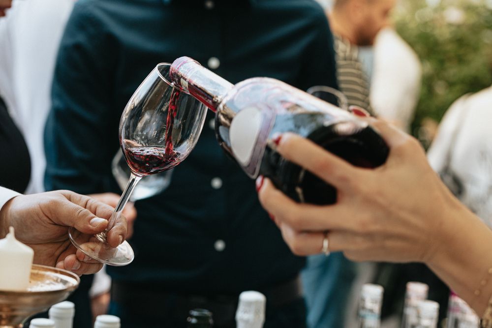 Una mujer está sirviendo vino en una copa durante una cata de vinos.