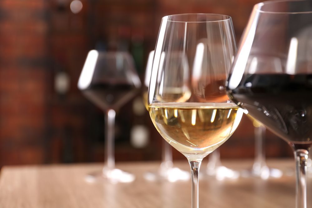 Una fila de copas de vino llenas de diferentes tipos de vino sobre una mesa.
