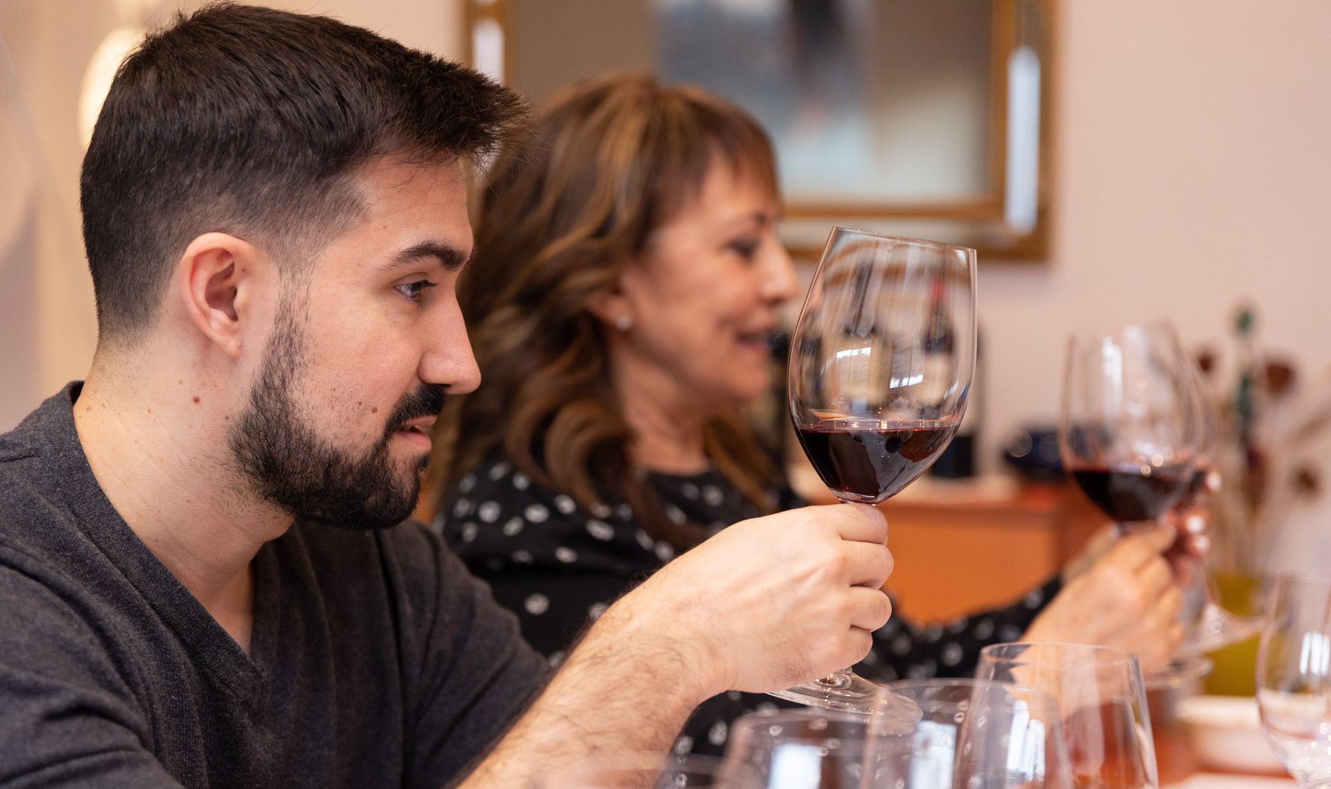 Un hombre y una mujer brindan con copas de vino en una mesa.