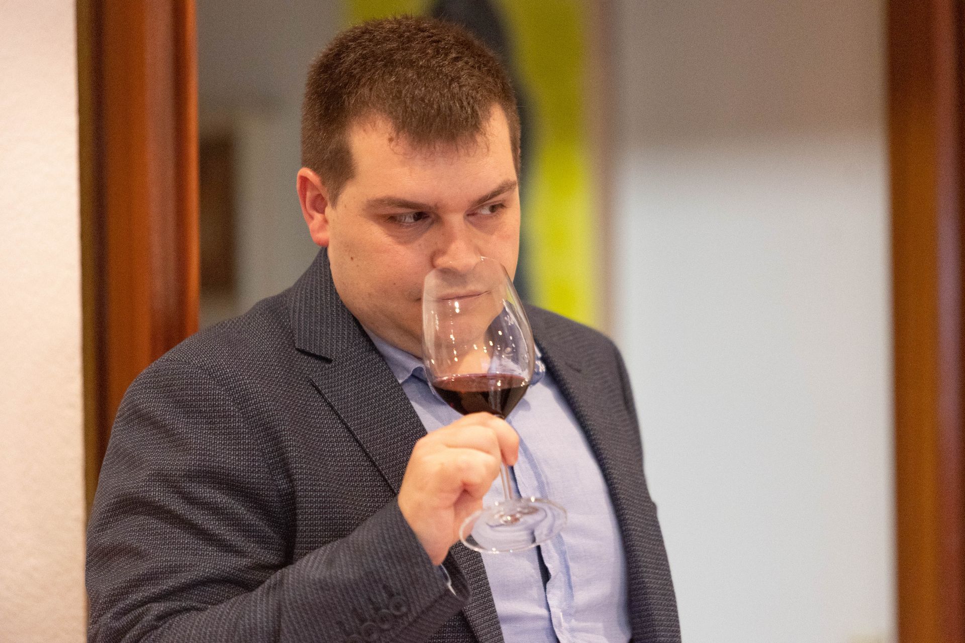 Un hombre con traje está bebiendo una copa de vino tinto.