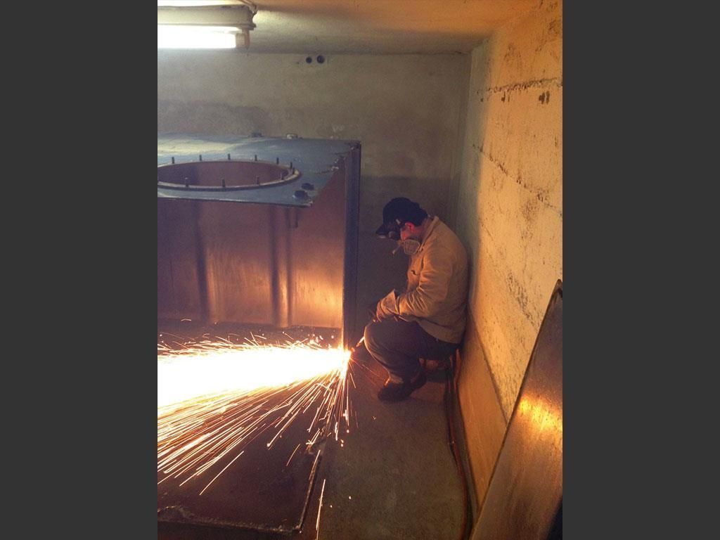 Ein Mann mit einer Schweißmaske schneidet ein Stück Metall