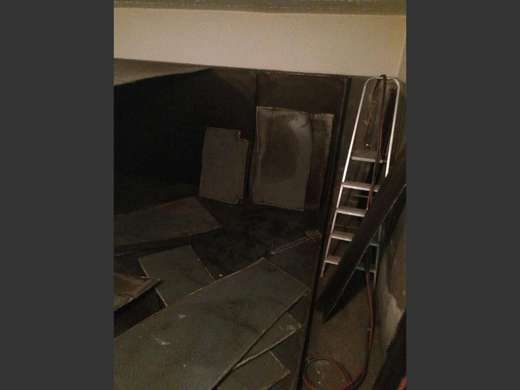 Eine Leiter lehnt an einer Wand in einem dunklen Raum