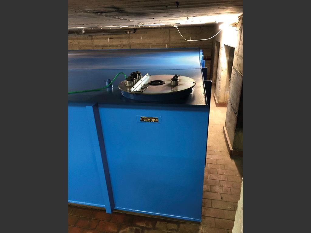 Ein blauer Behälter mit einem Metalldeckel steht in einem Raum