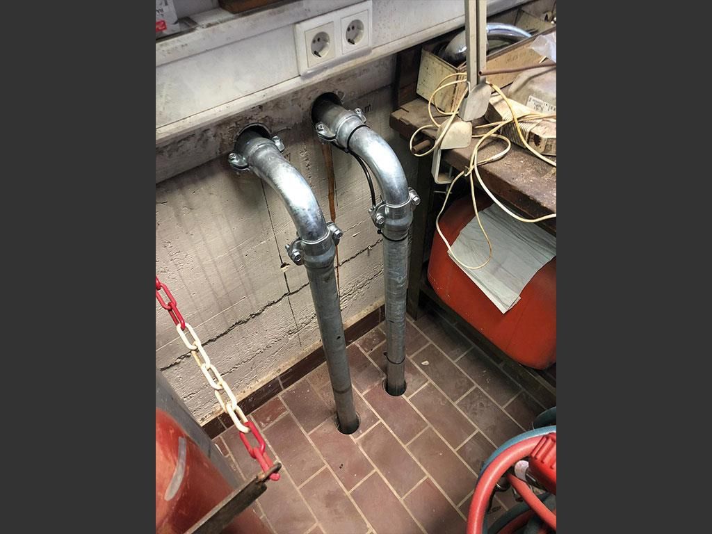 Zwei Metallrohre sind mit einer Wand in einem Raum verbunden