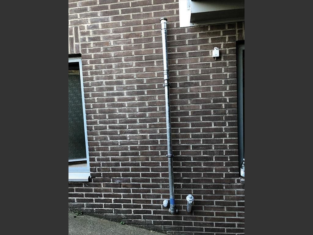 Eine Ziegelwand mit einem daran befestigten Rohr