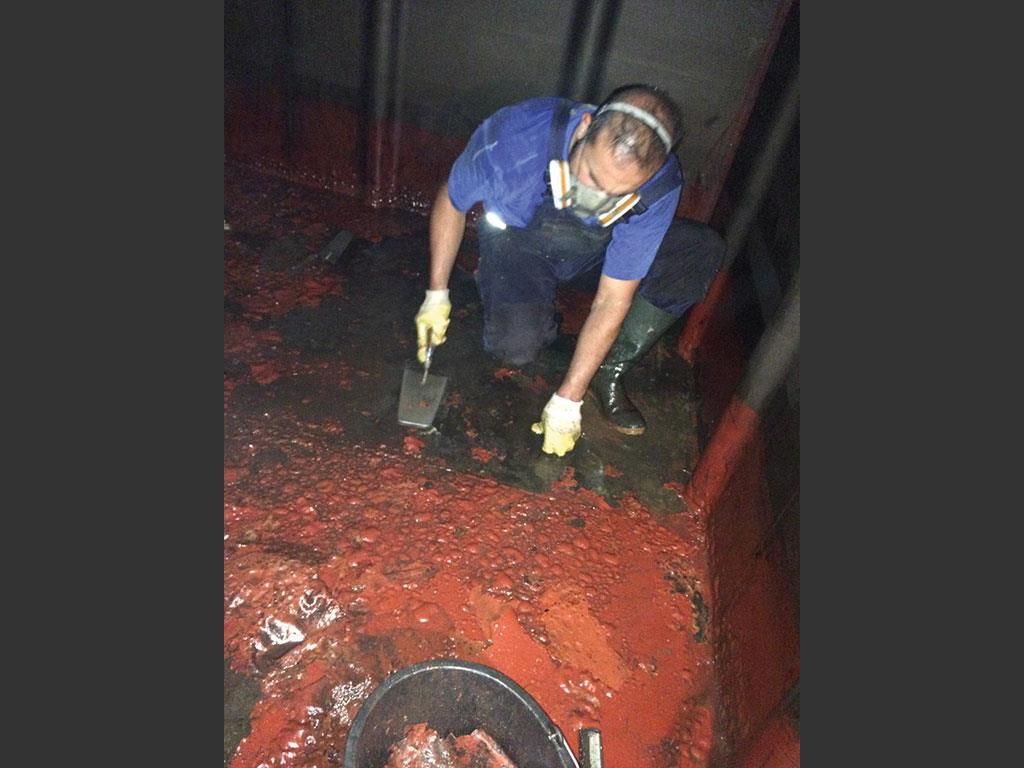 Ein Mann mit Maske und Handschuhen arbeitet an einer roten Oberfläche