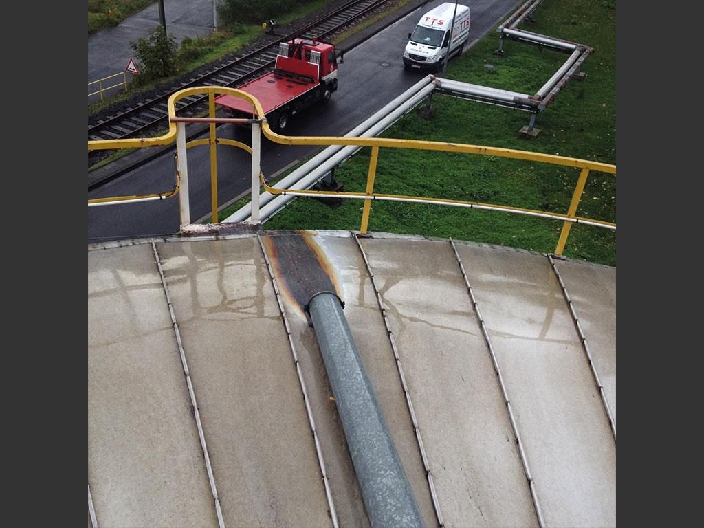 Ein roter Lastwagen fährt eine Straße entlang neben einem Geländer