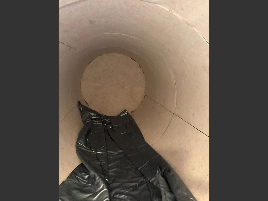 Eine schwarze Plastiktüte wird um die Innenseite eines Fasses gewickelt.