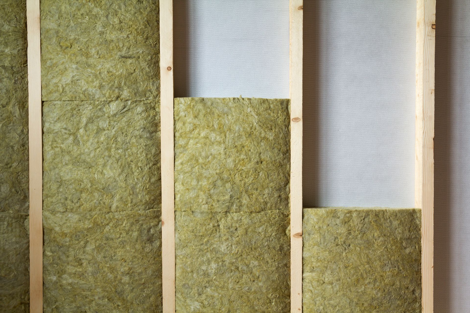 Mur intérieur en construction montrant la charpente en bois, l'isolation et le revêtement mural.
