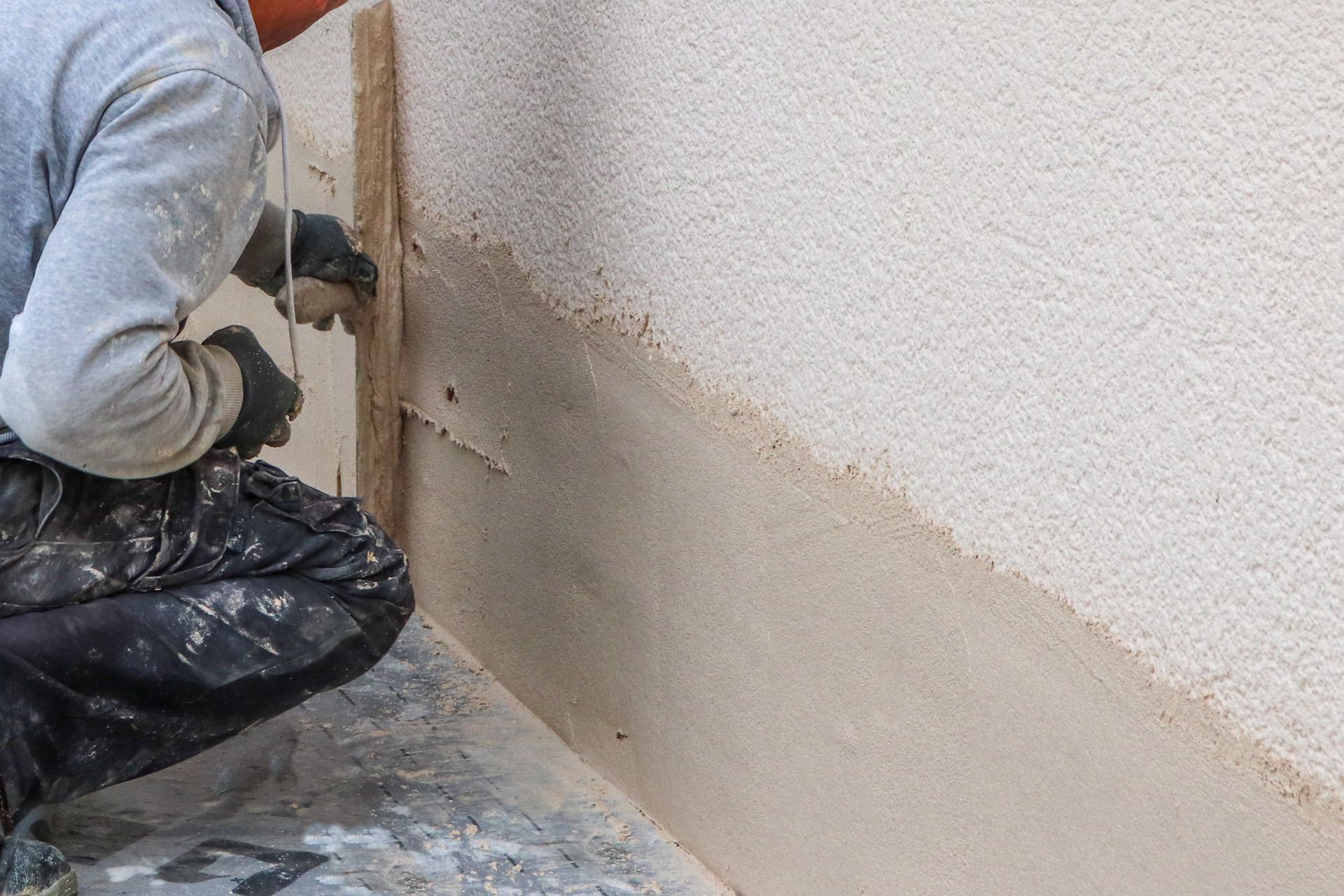 Personne appliquant du plâtre à la truelle sur un mur extérieur.