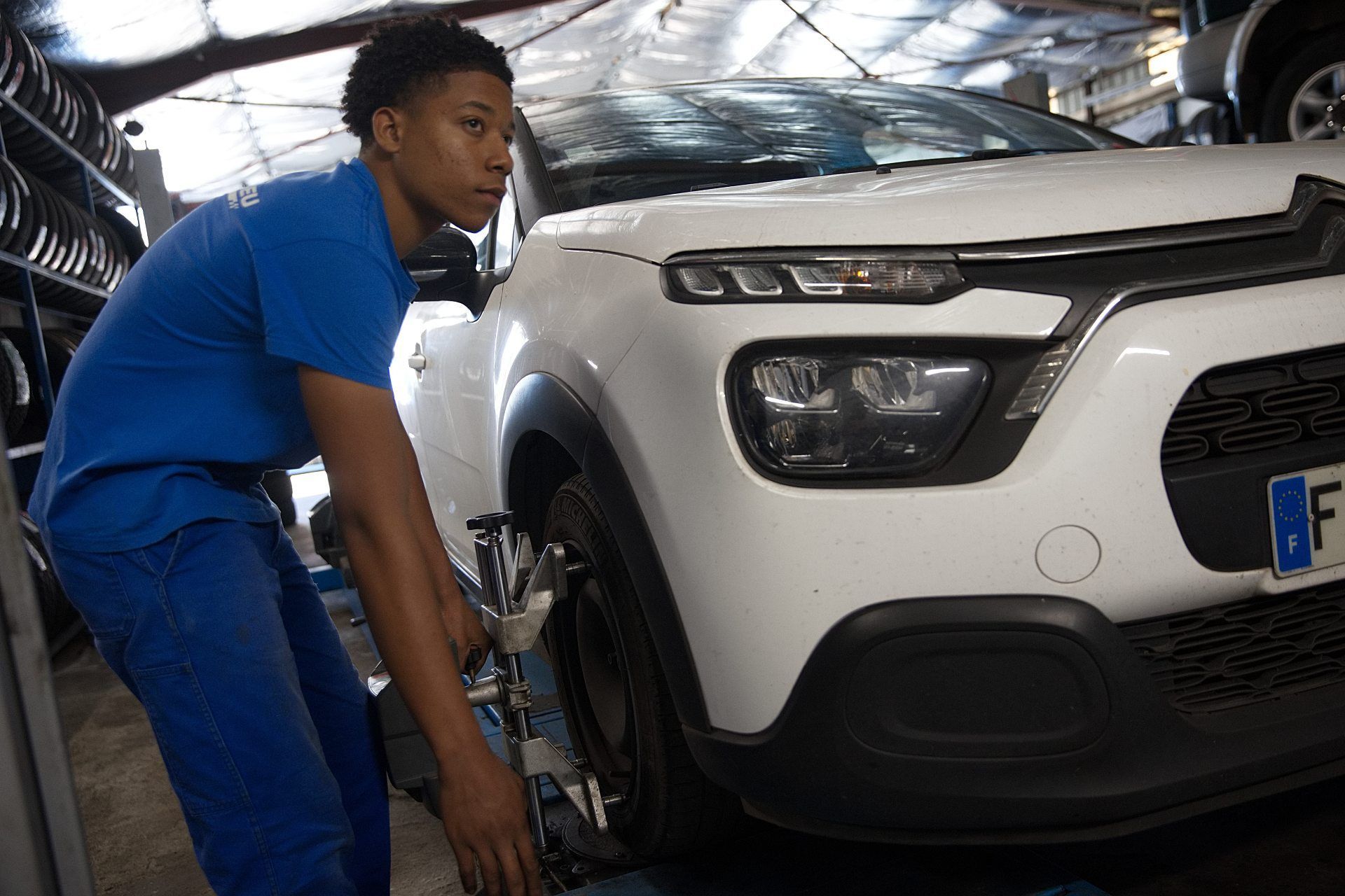 Technicien qui ajuste l'alignement d'une roue sur un citadine 