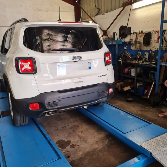 Véhicule blanc sur un pont de relevage dans le garage Inter Pneu