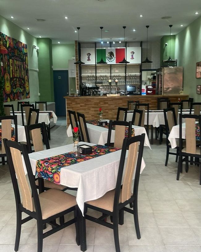Un restaurante con mesas y sillas y banderas en la pared.