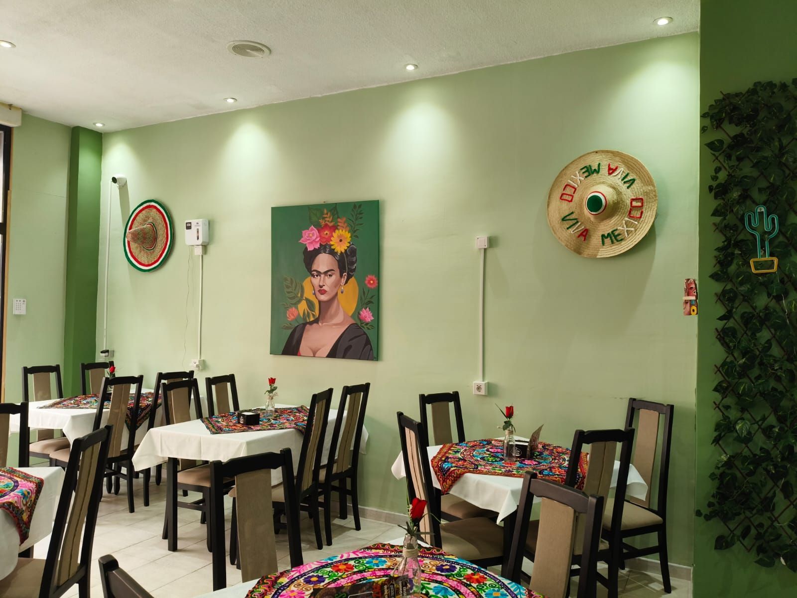Un restaurante con mesas y sillas y un cuadro de Frida Kahlo en la pared.