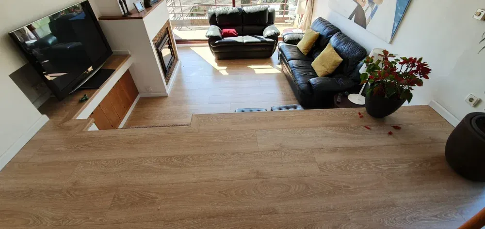 Una sala de estar con sofá, sillón, televisión y chimenea.