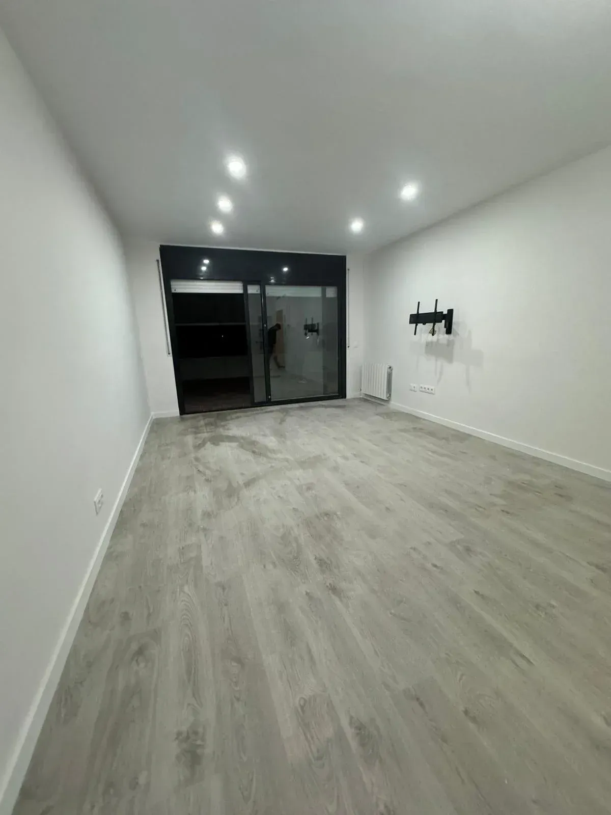 Una gran habitación vacía con suelo de madera y paredes blancas.