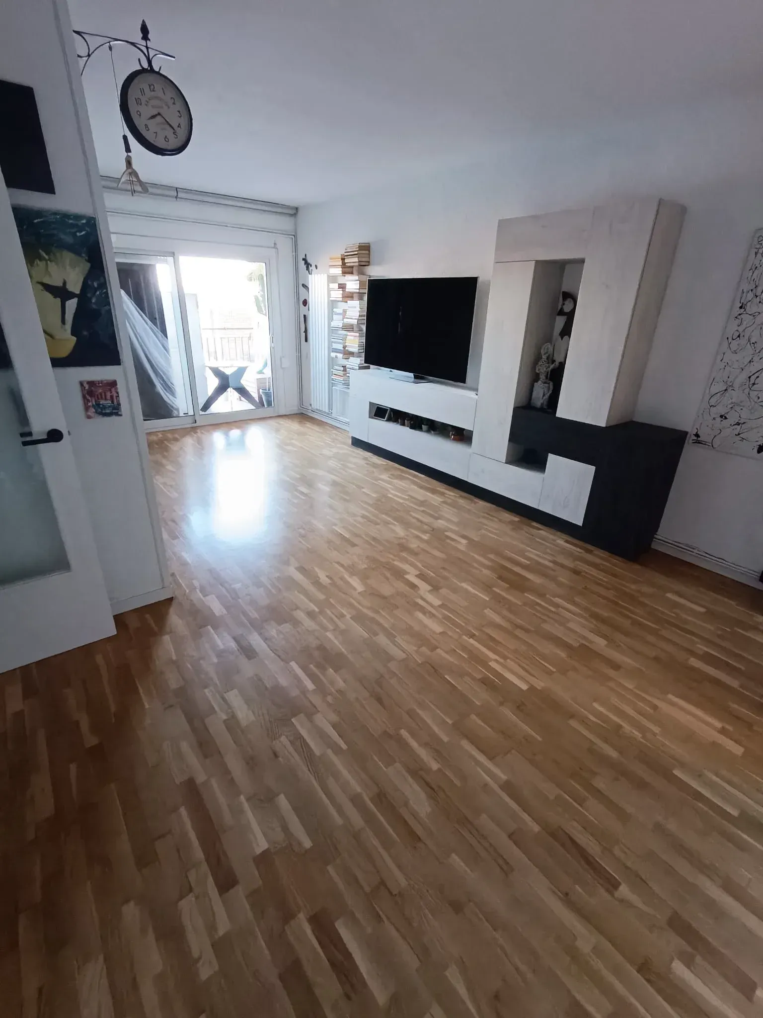 Una sala de estar con suelo de madera y TV de pantalla plana.