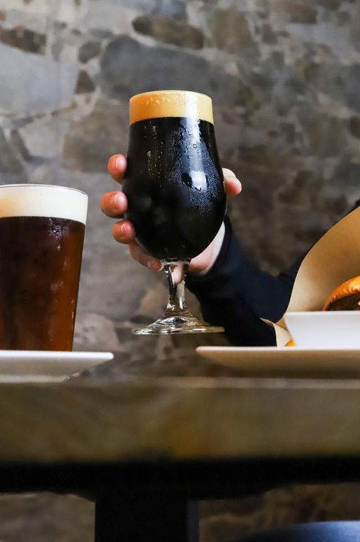 Una persona sostiene un vaso de cerveza en su mano.