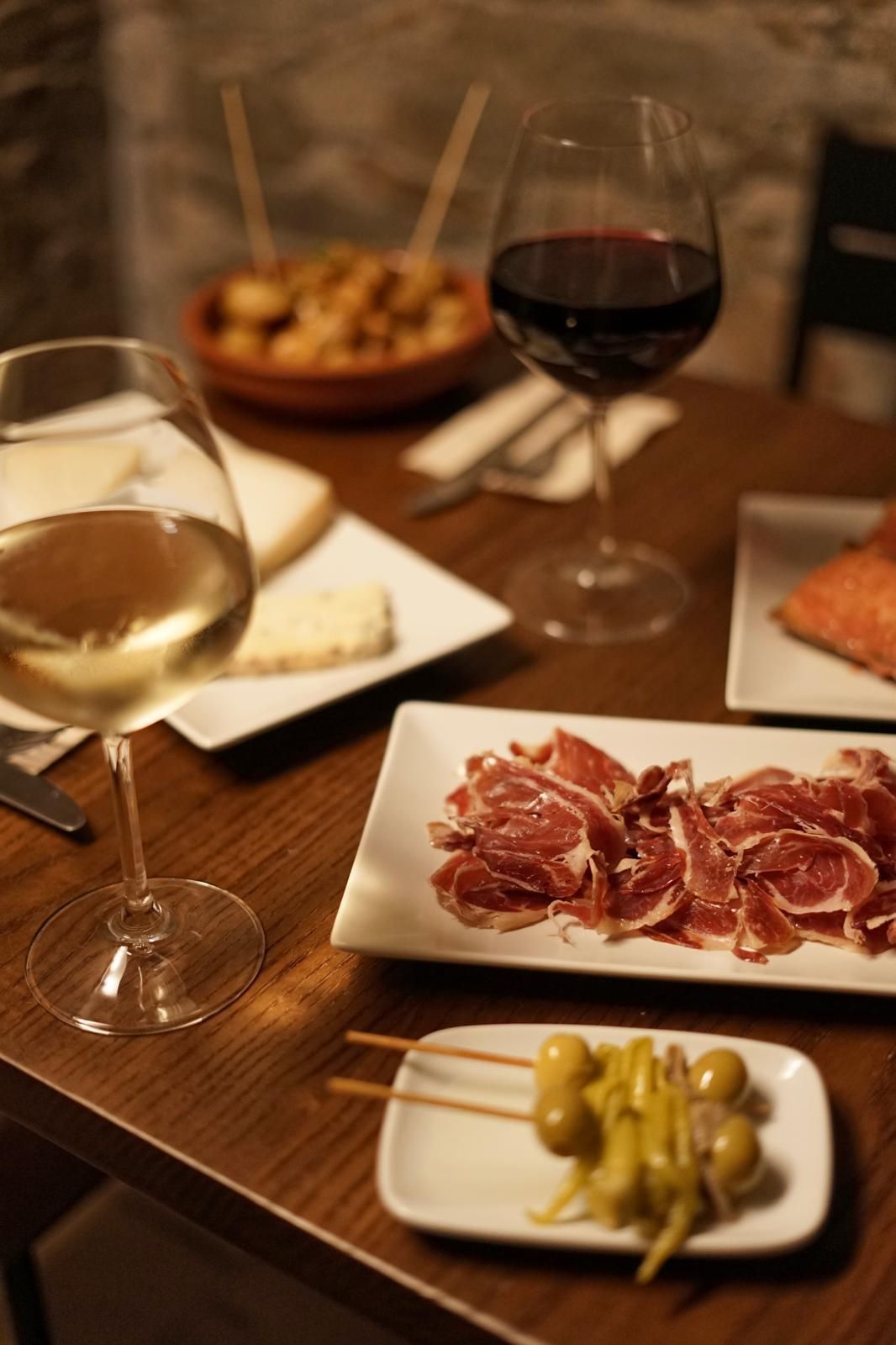 Una mesa con platos de comida y una copa de vino.