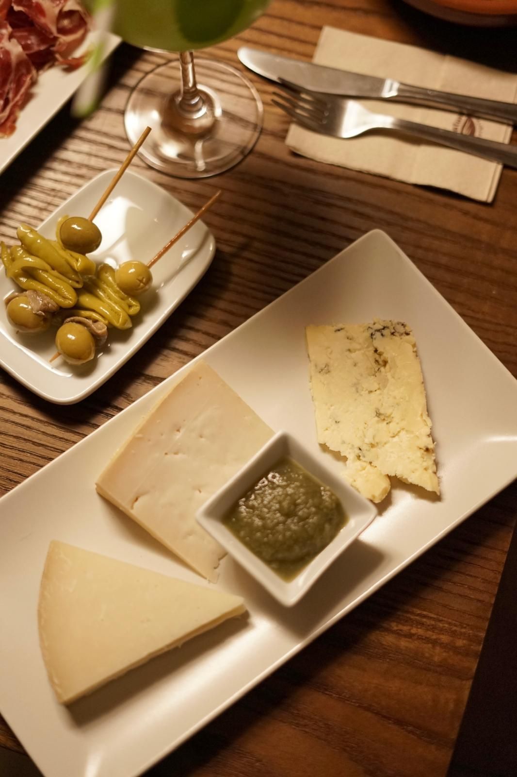 Un plato de queso y aceitunas en una mesa de madera.