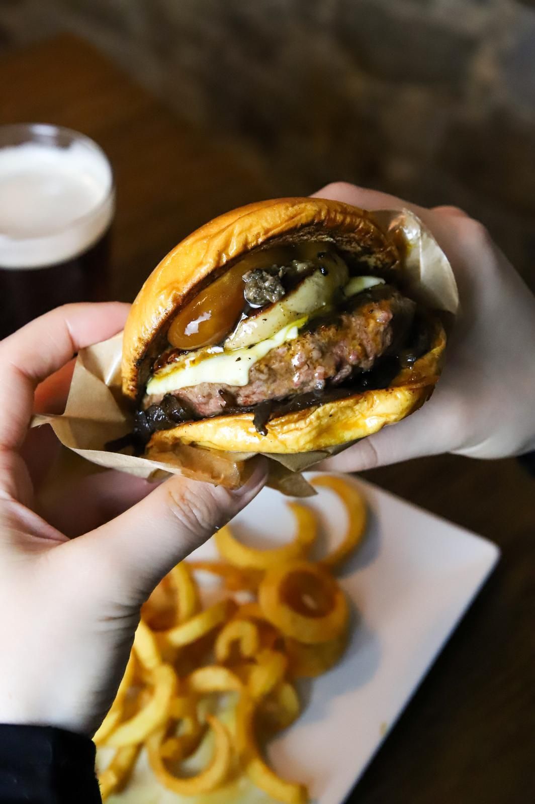 Una persona sostiene una hamburguesa y papas fritas en sus manos.