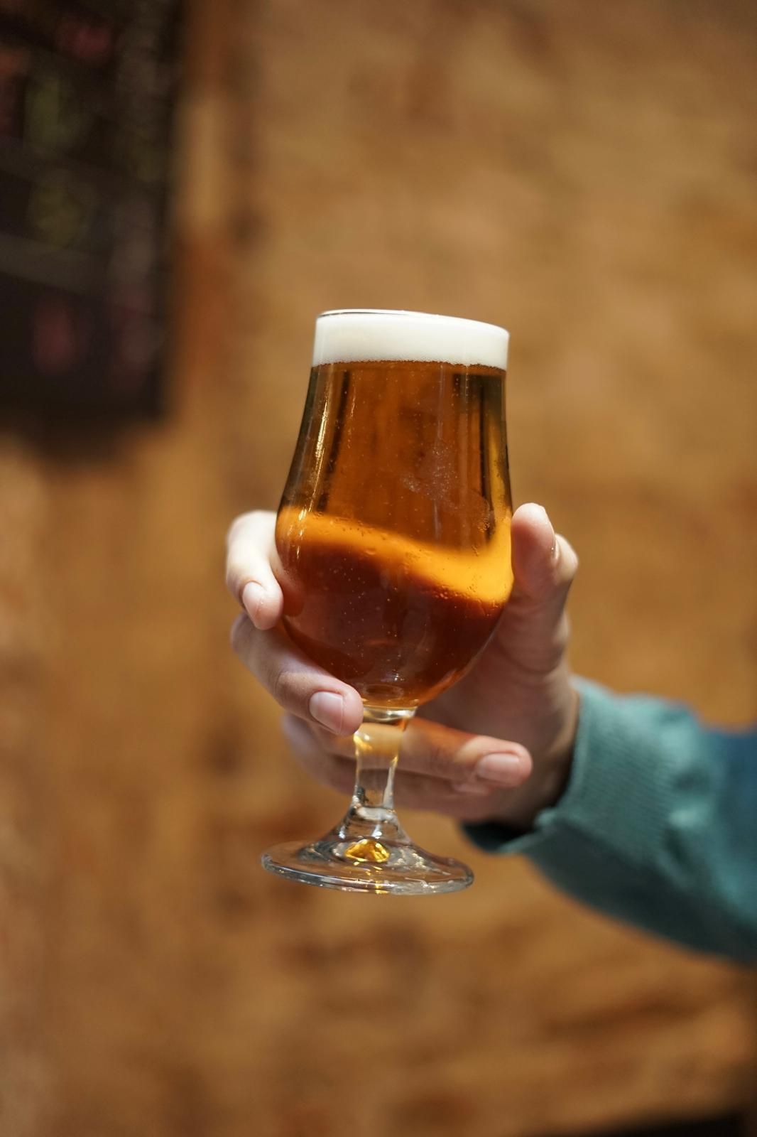 Una persona sostiene un vaso de cerveza en su mano.