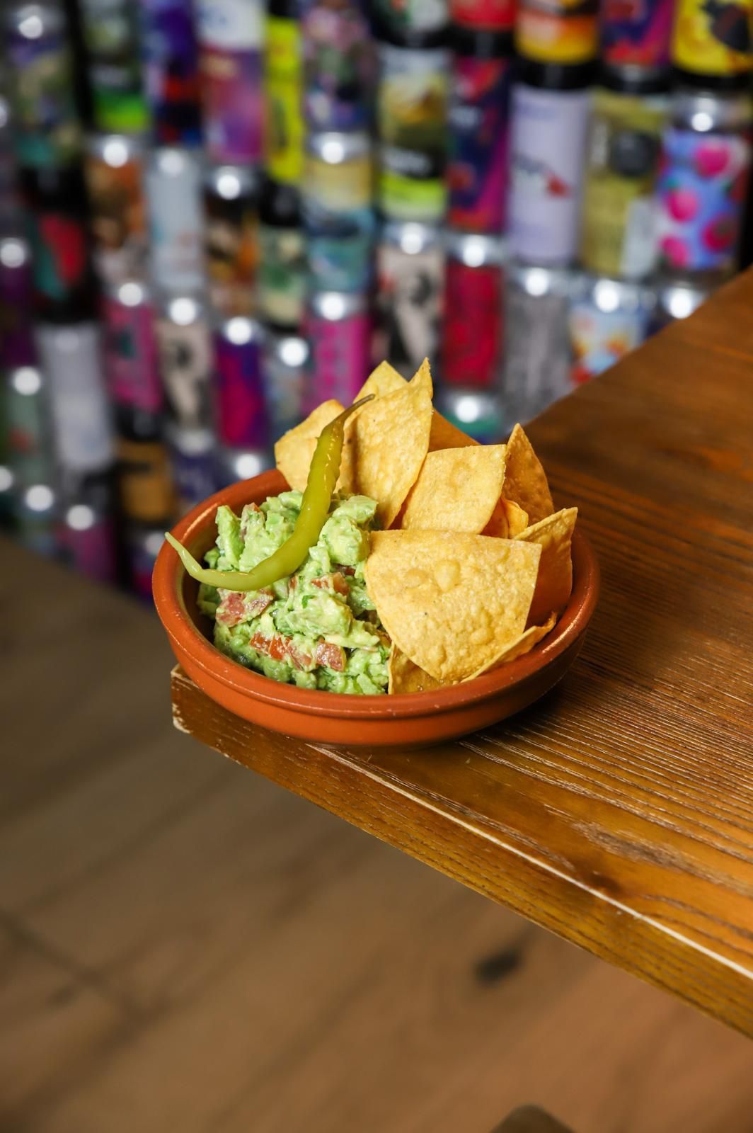 Un tazón de guacamole y chips de tortilla sobre una mesa de madera.